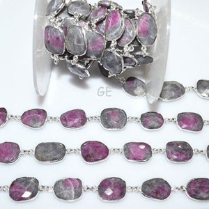 Può includere: Una catena d'argento con maglie in pietre preziose rosa e grigie. La catena è realizzata con pietre sfaccettate rettangolari con un connettore in metallo argentato tra ogni pietra.