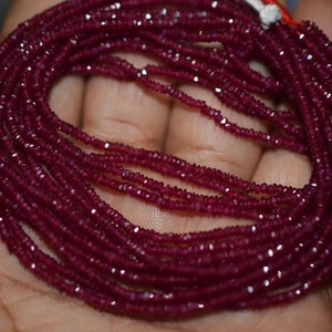 May include: A strand of deep red ruby beads, faceted and strung together. The beads are small and uniform in size, creating a smooth and elegant look.