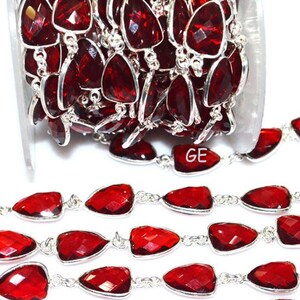 Puede incluir: Una hebra de cuentas de piedras preciosas rojas con eslabones de cadena plateados. Las cuentas son facetadas y tienen forma triangular. La cadena es plateada y tiene un diseño delicado. Las cuentas están enhebradas en una cadena plateada y están listas para ser utilizadas para la elaboración de joyas.