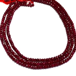 May include: A strand of deep red ruby beads, faceted and strung together to create a necklace or bracelet. The beads are uniform in size and shape, creating a smooth and elegant look.