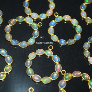 May include: A collection of 10 gold-plated opal pendant charms. Each charm is a circle of oval-shaped opals with iridescent colors. The charms are perfect for jewelry making.