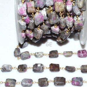 May include: Strands of raw, rectangular-cut gemstones in shades of gray, brown, and pink are strung together with delicate gold-colored chain. The gemstones are irregular in shape, adding a natural, organic feel to the jewelry. The gemstones are likely tourmaline.