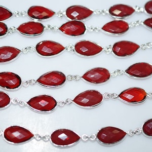 Puede incluir: Una hebra de cuentas de piedras preciosas rojas con conectores plateados. Las cuentas son facetadas y tienen forma de lágrima.