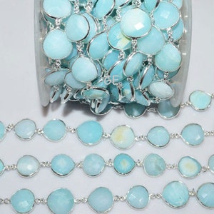 May include: A silver chain with light blue gemstone beads. The chain is made of metal and has a delicate design. The gemstones are round and have a smooth finish.