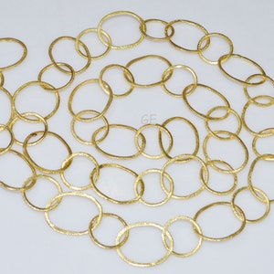 May include: A gold chain necklace made of oval-shaped links. The chain is textured and has a slightly hammered finish.