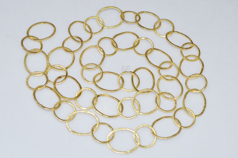May include: A gold chain necklace made of oval-shaped links. The chain is textured and has a slightly hammered finish.