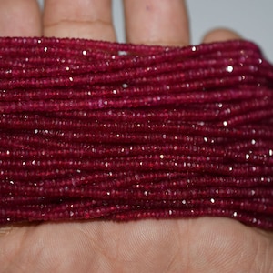 May include: A strand of deep red ruby beads, faceted and strung together. The beads are small and uniform in size, creating a smooth and elegant look.