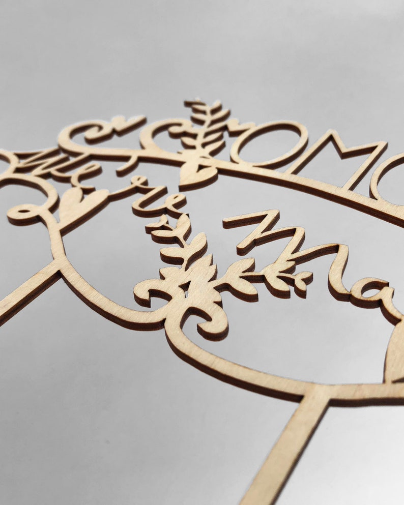 May include: Wooden cake topper with the words "Mr & Mrs" and a floral design.