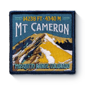 May include: A blue and yellow embroidered patch with the text "Mt Cameron" and "Mosquito Range, Colorado". The patch also includes the elevation of the mountain, "14238 FT - 4340 M".