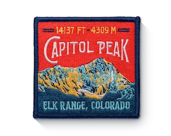 May include: A blue and red embroidered patch with the text "Capitol Peak" and "Elk Range, Colorado". The patch also includes the elevation of the peak in feet and meters: "14137 FT - 4309 M".