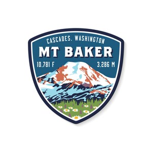 Op de afbeelding: Een blauwe en witte sticker met een bergketenillustratie en de tekst "CASCADES, WASHINGTON MT BAKER 10,781 ft 3,286 m".