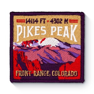 Può includere: Una toppa ricamata con un bordo viola, che presenta una scena di montagna con una cima innevata. Il testo "14,114 FT. 4302 M" è sopra il testo "PIKES PEAK" in lettere bianche su uno sfondo beige. Il testo "FRONT RANGE, COLORADO" è in lettere rosse su uno sfondo viola.