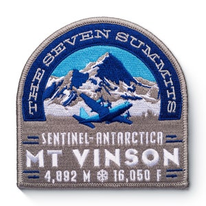 May include: A grey and blue embroidered patch with the text "The Seven Summits" and "Sentinel - Antarctica - Mt Vinson - 4,892 M - 16,050 F" around a depiction of a mountain range and a plane.