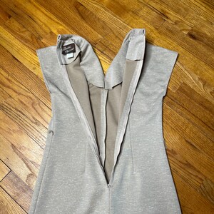 May include: A beige sleeveless dress with a zipper down the back. The dress has a small brown label that says "Debbie Classics".