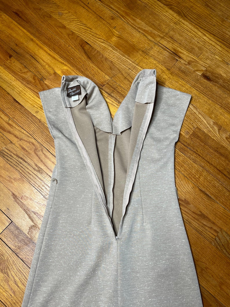 May include: A beige sleeveless dress with a zipper down the back. The dress has a small brown label that says "Debbie Classics".