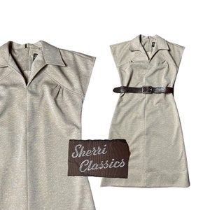 May include: A beige sleeveless dress with a collared neckline and a brown belt. The dress has a textured fabric and a slightly flared skirt. The dress is labeled "Sherri Classics".