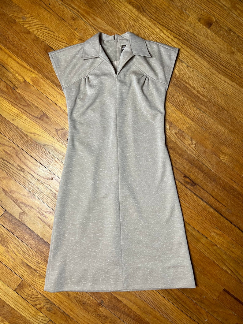 May include: A light gray sleeveless dress with a collared neckline and a slightly fitted silhouette.