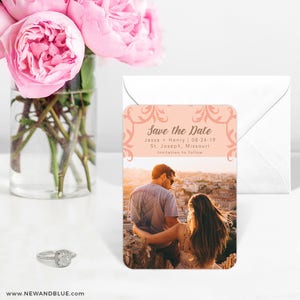 May include: Peach-colored save the date magnet with a floral design. The magnet features a photo of a couple looking out over a city skyline. The text reads "Save the Date", "Jessa + Henry | 08-24-19", "St. Joseph, Missouri", and "Invitation to follow".