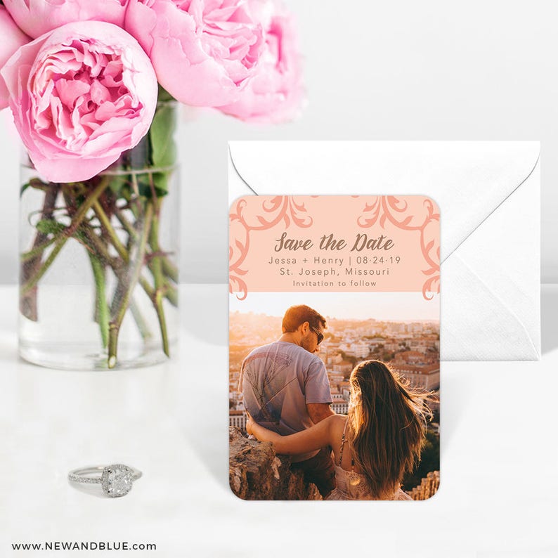 May include: Peach-colored save the date magnet with a floral design. The magnet features a photo of a couple looking out over a city skyline. The text reads "Save the Date", "Jessa + Henry | 08-24-19", "St. Joseph, Missouri", and "Invitation to follow".