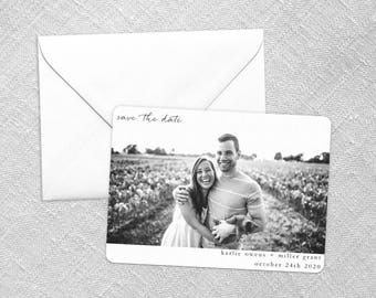 May include: Black and white save the date card with a photo of a couple in a field. The text reads "save the date" and "Karlie Owens + Miller Grant October 24th 2020".