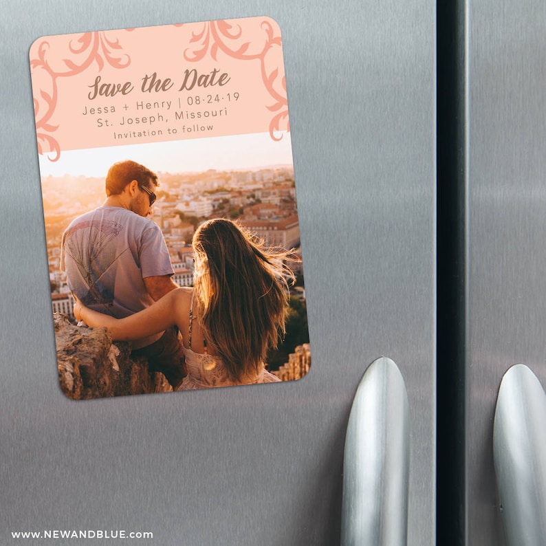 May include: Save the Date magnet with a peach background and a floral design. The magnet features a photo of a couple sitting on a ledge overlooking a city. The text on the magnet reads "Save the Date", "Jessa + Henry", "08-24-19", "St. Joseph, Missouri", and "Invitation to follow".