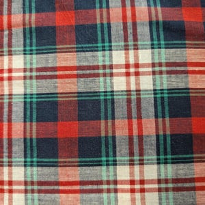 May include: A woven fabric featuring a classic plaid pattern with intersecting horizontal and vertical lines. The design consists of a repeating grid of deep navy blue, vibrant red, bright emerald green, and off-white stripes on a textile surface.
