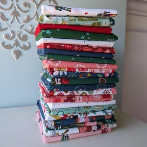May include: A tall, vertical stack of folded fabric squares featuring various holiday-themed patterns. The textiles display festive motifs including nutcrackers, wrapped gift boxes, Christmas ornaments, pine branches, and stars in red, green, blue, pink, and white.