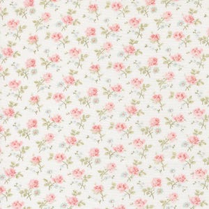 May include: A fabric with a repeating floral pattern. The design features pink roses, small blue flowers, and green leaves on a cream-colored background. The roses are in full bloom, and the overall effect is delicate and feminine.