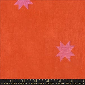 May include: A vibrant orange fabric featuring a repeating pattern of light pink eight-pointed stars. A black ruler at the bottom edge shows a scale of 7 inches, with the text RUBY STAR SOCIETY printed repeatedly along the bottom margin.