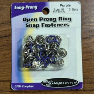 May include: A package of purple size 16 open prong ring snap fasteners. The package includes 10 sets of fasteners, each measuring 7/16" (11mm). The packaging is labeled "Long-Prong" and "The Snap Source."