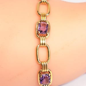 May include: A gold chain bracelet with three square-shaped amethyst gemstones. The bracelet is made of 14k gold and has a polished finish.