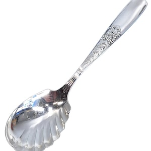 May include: A silver sugar spoon with a scalloped bowl and an ornate floral design on the handle.