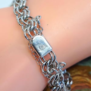 Op de afbeelding: Een zilveren kettingarmband met een sluiting waarop "Elco Sterling" staat.