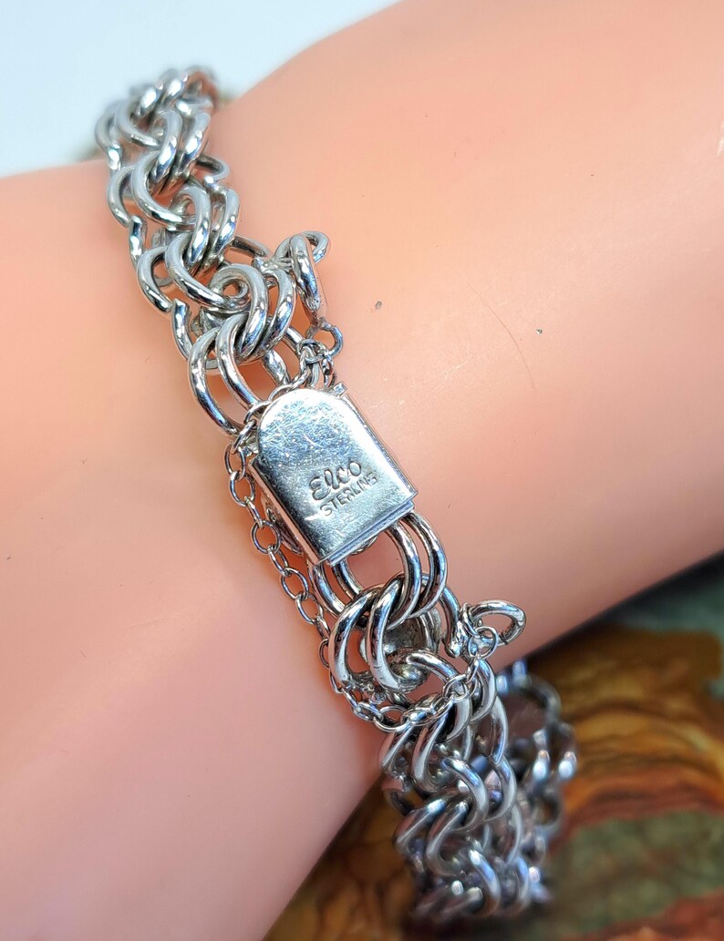 Op de afbeelding: Een zilveren kettingarmband met een sluiting waarop "Elco Sterling" staat.