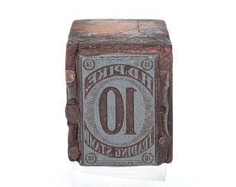 May include: A wooden block with a metal stamp that reads "Trading Stamps D. Pike 10". The block is brown and has a worn, aged appearance.