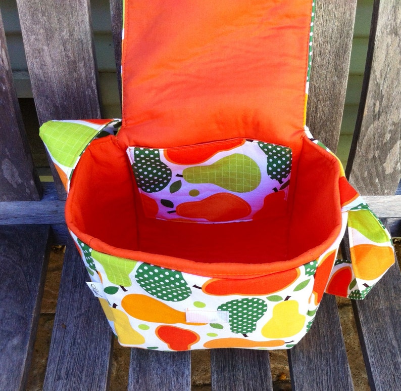 May include: A handmade fabric bag with a flap, featuring a vibrant pear pattern in orange, yellow, and green on a white background. The interior is bright orange, and a smaller pocket with a pear print is visible.