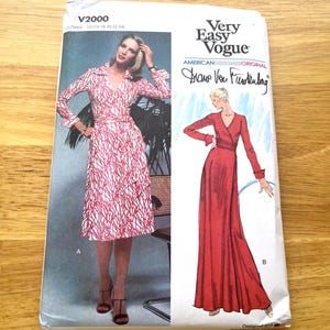 May include: A Very Easy Vogue sewing pattern envelope V2000 for a wrap dress by Diane Von Furstenberg. The front shows two views: view A is a knee-length dress with a red and white abstract pattern, and view B is a floor-length solid red dress.