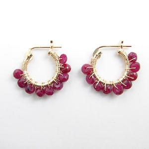 Puede incluir: Aretes de aro de oro con un racimo de piedras preciosas de color rojo rubí.