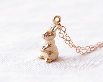 May include: A gold-toned rabbit pendant necklace with a delicate chain. The rabbit is standing upright with its ears perked up.