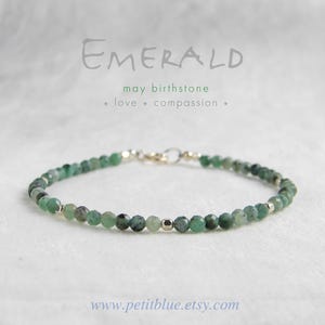 May include: Emerald beaded bracelet with silver accents. The bracelet features small, faceted green beads strung together with a silver clasp. Text on the image reads "EMERALD may birthstone love compassion".