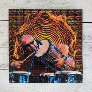 May include: A psychedelic image of a man playing a set of conga drums. The background is a swirling pattern of orange, yellow, and black. The man is wearing a black shirt and sunglasses.