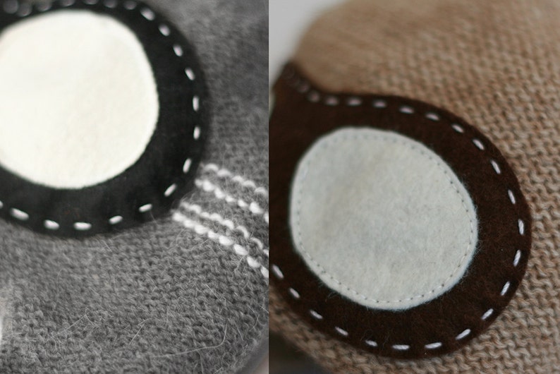 May include: Two close-up images of knitted fabric with a circular patch sewn on. The patch on the left is black with white stitching and a white circle in the center. The patch on the right is brown with white stitching and a white circle in the center.