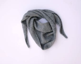 May include: A gray knitted scarf with long, pointed ends. The scarf is folded in half and has a textured pattern.