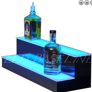 May include: Two-tiered black LED lighted bottle display shelf with blue LED lights. The top shelf has a green bottle and the bottom shelf has a blue bottle.