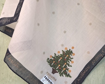 May include: A white handkerchief featuring a dark border with the text Merry Christmas, a central Christmas tree graphic with lit candles, and small gold snowflake patterns. A Renoma Paris label is attached to the fabric corner.