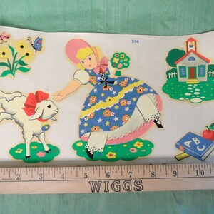 May include: A vintage children's illustration featuring a girl in a blue and yellow dress with a pink hat, a white lamb with a red bow, a small schoolhouse, and an ABC book with a red apple. The illustration is printed on a white background.