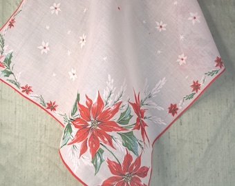 May include: A white square handkerchief with a red rolled hem, featuring a large poinsettia floral print in the corner and smaller scattered white poinsettia motifs across the fabric. A Burmel Original label is attached to the corner.