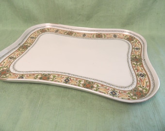 May include: A white porcelain serving tray with a scalloped edge and a decorative border of green, gold, and blue floral patterns.