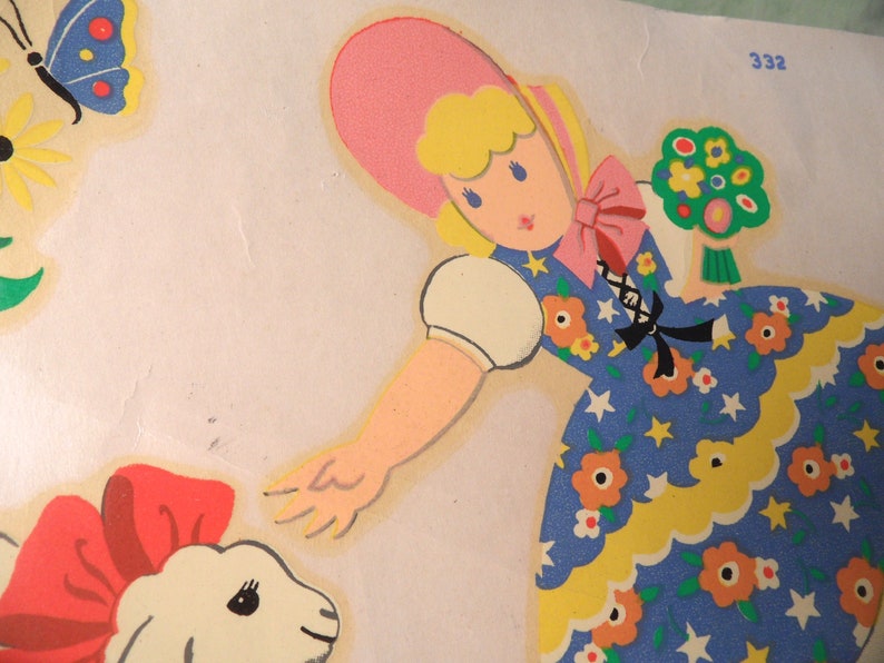 May include: A vintage illustration of a girl wearing a pink hat and a blue dress with white stars and yellow flowers. She is holding a bunch of green flowers and reaching out to a white lamb with a red bow.