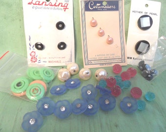 May include: Assortment of buttons in various colors and styles, including green, blue, pink, white, and black. Some buttons are on cards with the text "Lansing", "Costumakers", and "Mother of Pearl".